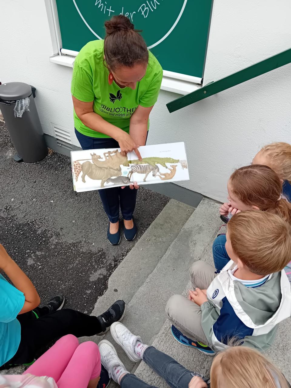 Frau liest aus Bilderbuch vor