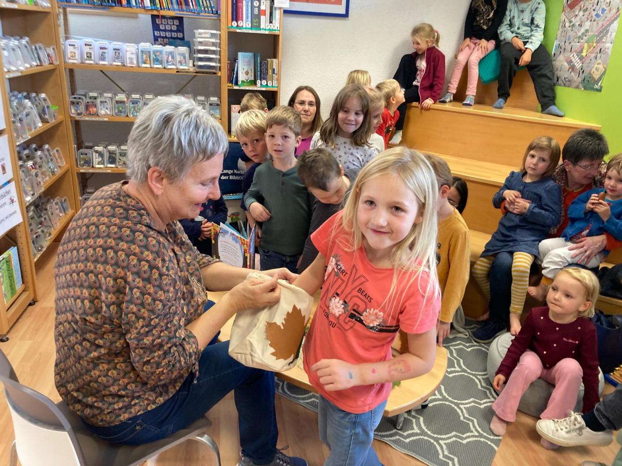 Frau lässt Kindern etwas aus einem Sackerl ziehen 