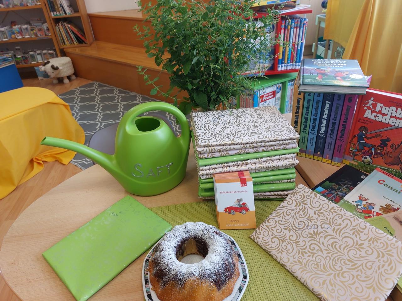 Gießkanne, Kuchen und Packerl auf einem Tisch