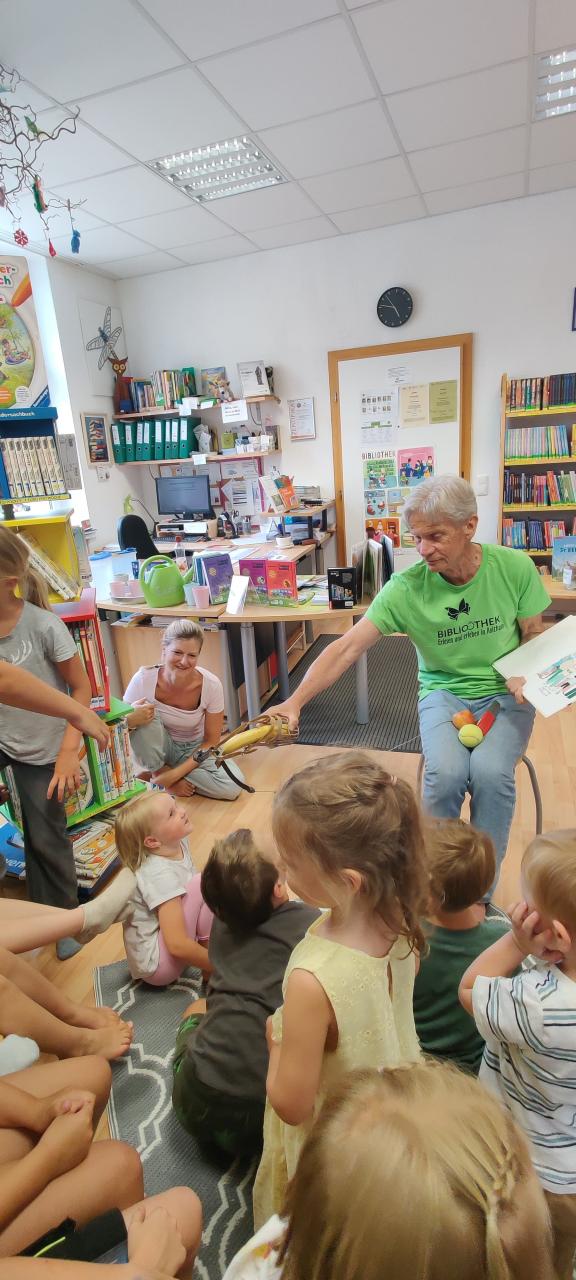 Mann liest und hält Kindern eine Banane hin