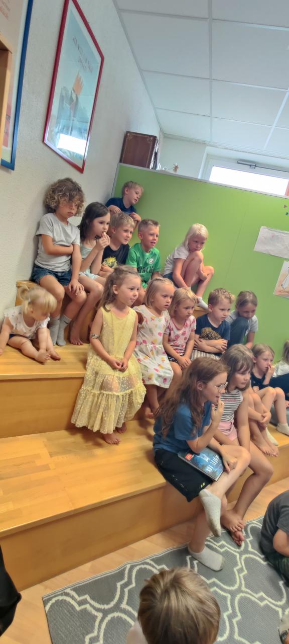 Kinder sitzen auf einer Treppe und hören zu