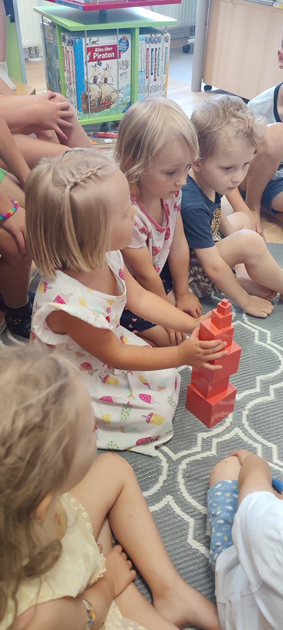 Kinder sitzen vor roten Bausteinen